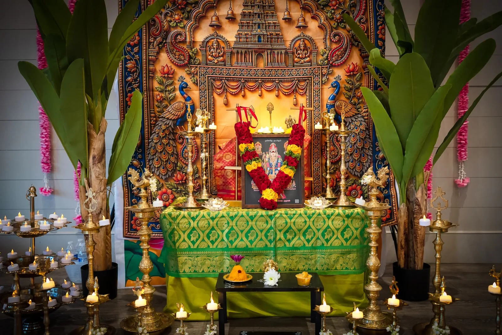 Murugan altar illuminated with lamps and flowers